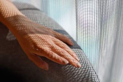 Cropped hand of woman on sofa at home