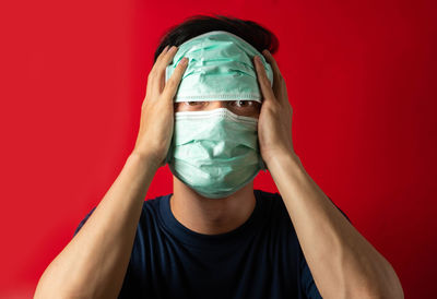 Portrait of person covering face against red background