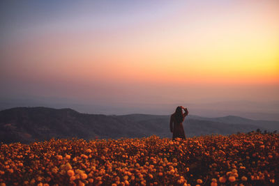 Man standing on field against sky during sunset