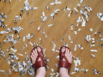 Low section of person standing amidst confetti on floor