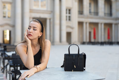 Portrait of young woman using mobile phone in city