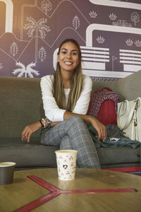 Portrait of young woman sitting on sofa at home