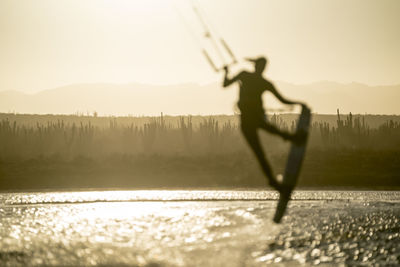 Young female athlete kiteboarding at sunset in la ventana, mexico