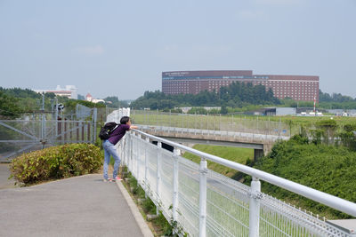 Rear view of people on railing in city against sky