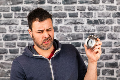 Portrait of man holding camera against wall