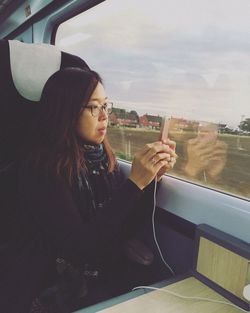Woman photographing using smart phone in train