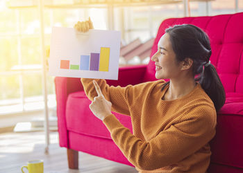 Woman looking away while sitting on table