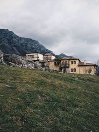 Houses on mountain against cloudy sky