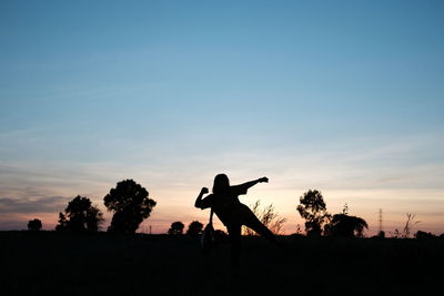 Silhouette people on field against sky during sunset