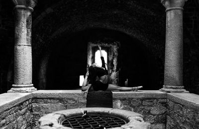 Woman doing splits on wall in historical building