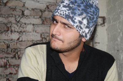 Portrait of young man wearing knit hat against brick wall