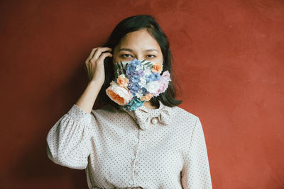 Portrait of woman covering face against wall