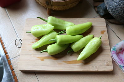 High angle view of green chili peppers on cutting board