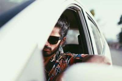 Portrait of young man wearing sunglasses sitting in car