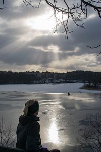 Rear view of girl standing on lake during winter