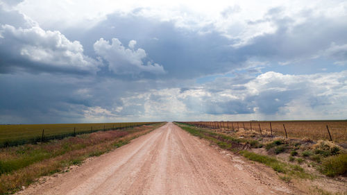 Road amidst agricultural field against sky