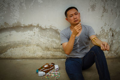 Mature man sitting by narcotics against wall