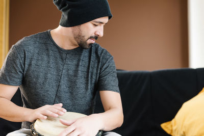 Man playing drum while sitting on sofa