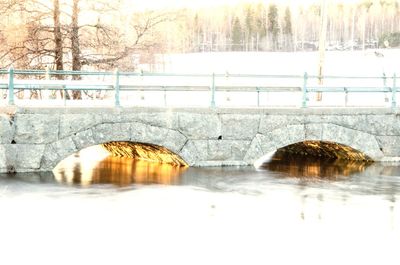 Arch bridge over river during winter