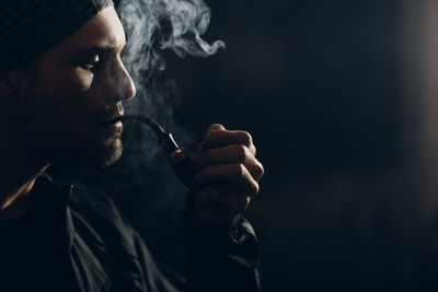 Man smoking cigarette against black background