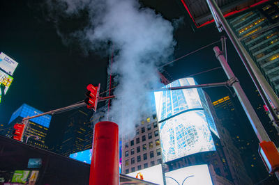 Low angle view of smoke stack against buildings in city