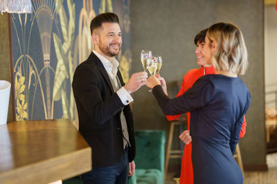 Smiling friends toasting wines at bar