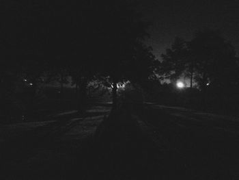 Empty road along trees at night