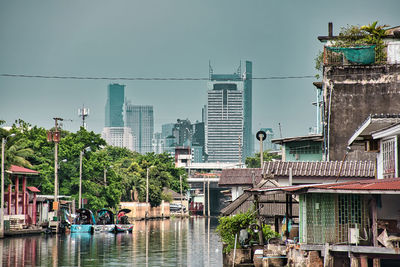 Buildings by river against sky in city