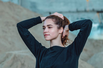 Graceful young woman lifting her hair with both hands