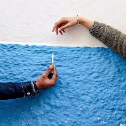 Close-up of hand holding cigarette in sea