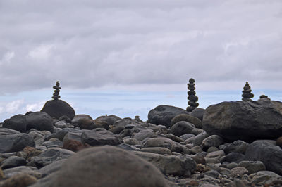 Stone stack on rocks by sea against sky