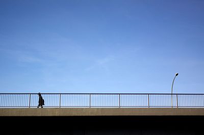 People standing on railing against clear sky