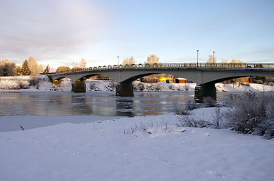 Arch bridge over river against sky during winter