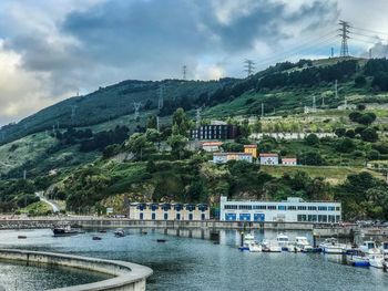 Scenic view of river by buildings against sky