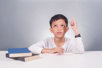 Portrait of boy sitting on table against wall