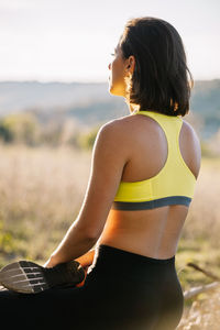 Rear view of woman sitting on field