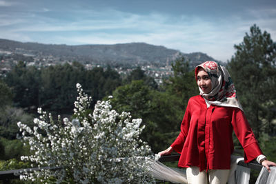 Woman in hijab standing against trees