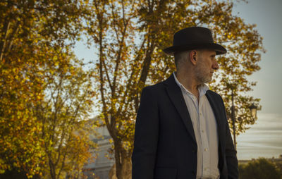 Portrait of adult man in suit and hat on street with autumn trees. madrid, spain