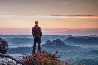 Rear view of man looking at mountains during sunset