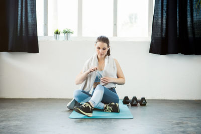 Young woman using mobile phone while sitting on floor at home
