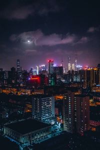 Illuminated buildings in city against sky at night