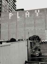 Rear view of man sitting against wall of building