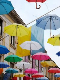 Multi colored umbrellas hanging in row against sky