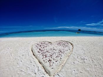 Heart shape on beach against blue sky