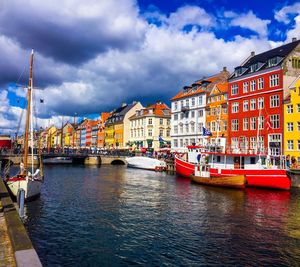 Sailboats moored on river by buildings in city against sky