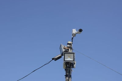 Low angle view of telephone pole against clear blue sky