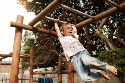 Low angle view of boy hanging at park