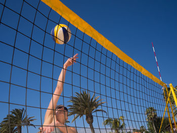 Woman playing volleyball at beach against sky