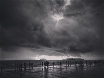 Silhouette people on beach against sky during sunset