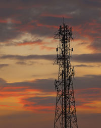 Low angle view of electricity pylon against sky during sunset